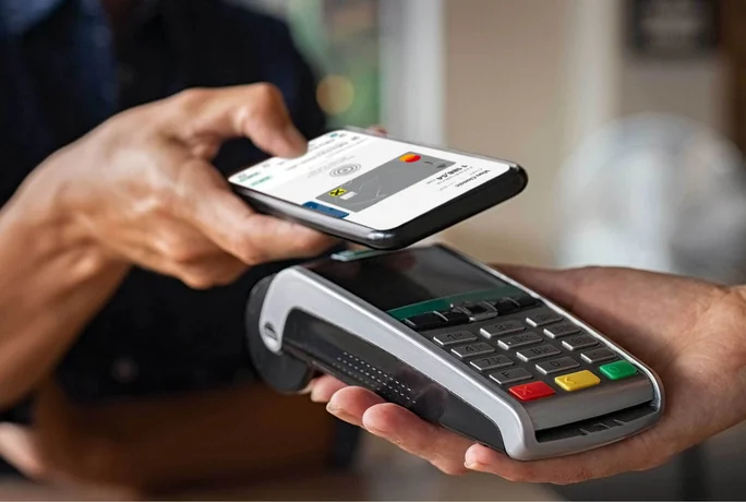 Close-up of a mobile payment transaction: someone is holding a smartphone with a digital credit card against a card terminal. This modern, secure payment method enables fast, cashless transactions.
